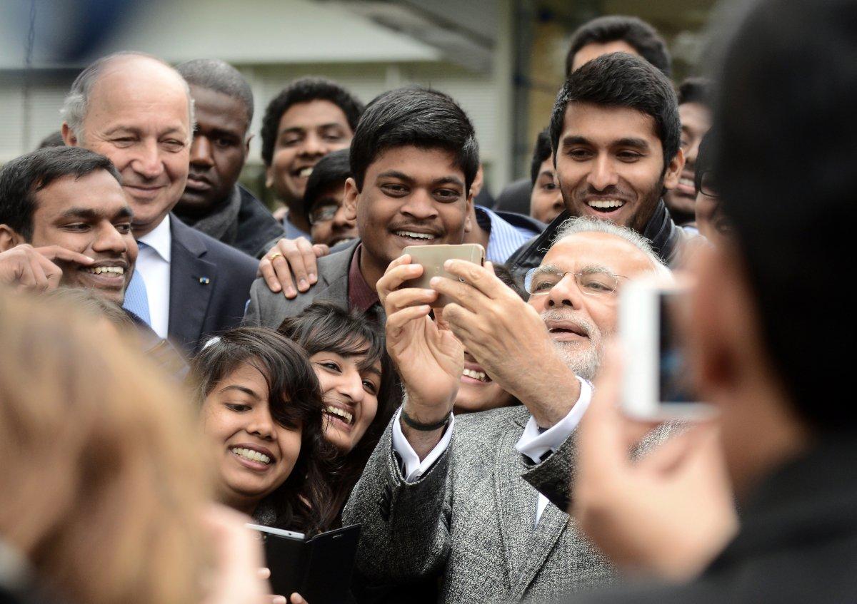 An April 2015 file photo from France showed Indian Prime Minister Narendra Modi taking a selfie with a group of Indian people studying abroad there. India suffered disproportionate selfie-deaths, a study found. (REMY GABALDA/AFP/GETTY IMAGES)