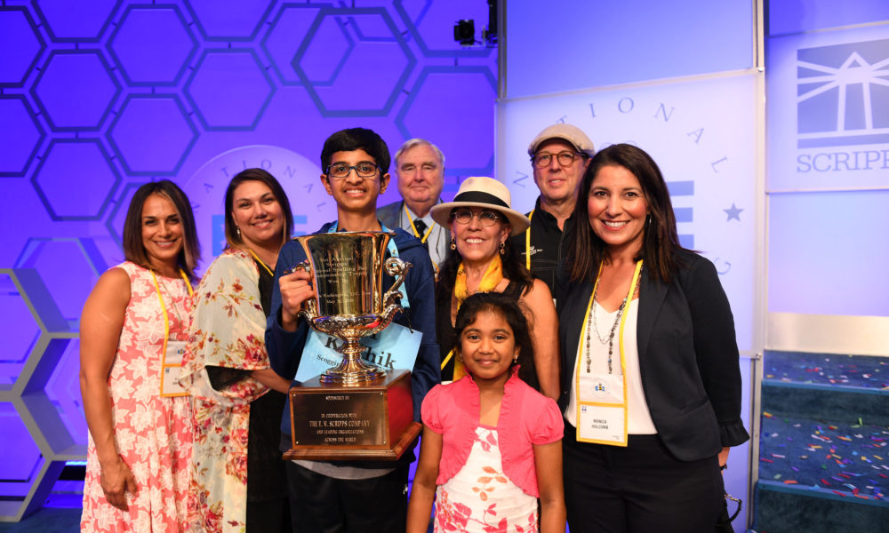 Karthik Nemmani surrounded by family, holding his Championship Trophy (Photo: Scripps Spelling Bee)